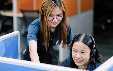 Beyond Limits staff member guiding a colleague with headset at a contact center workstation in Clarkfield, Philippines